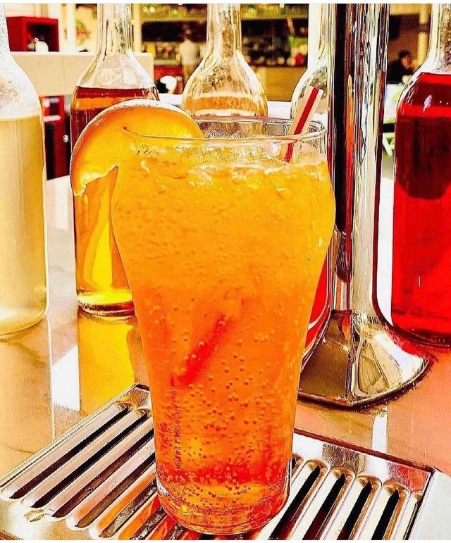 A tall glass of orange Italian soda at the fountain.