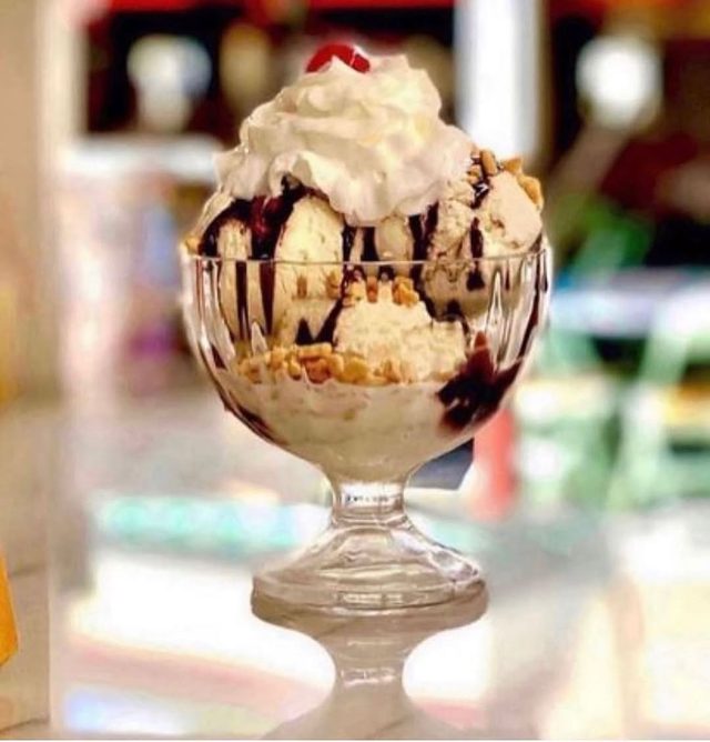 A sundae in a footed glass with chocolate sauce and whipped cream.