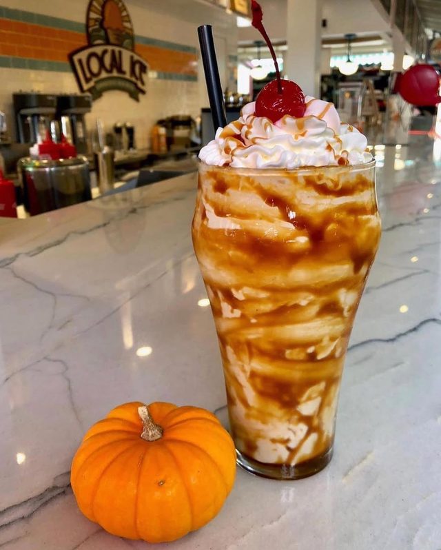 A tall caramel sundae glass on the marble counter.