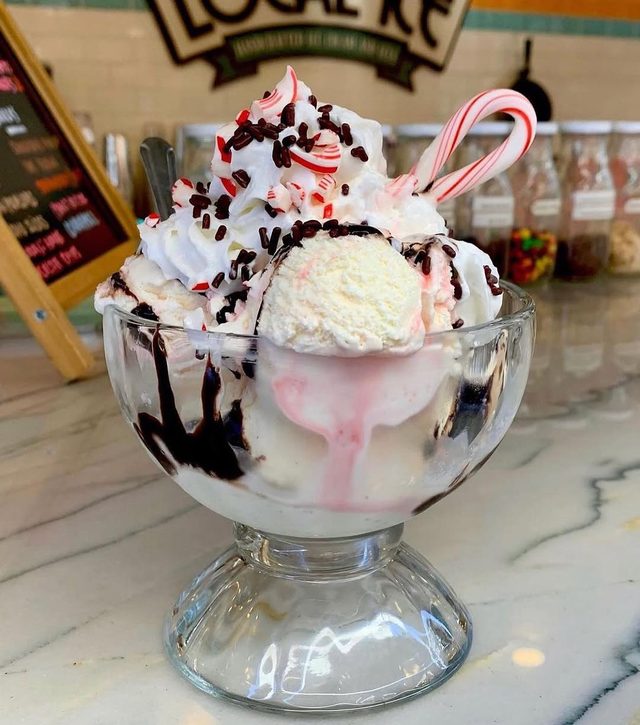 A sundae in a footed glass with whipped cream and a candy cane.