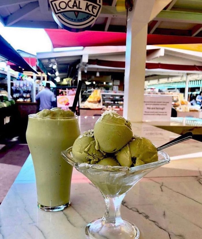 Scoops of pale green ice cream in a glass coupe, the market behind.