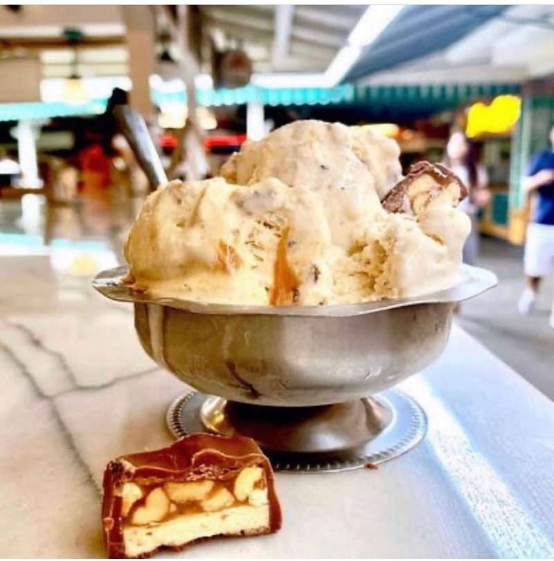 Scoops in a silver dish with a wafer biscuit, the market behind.