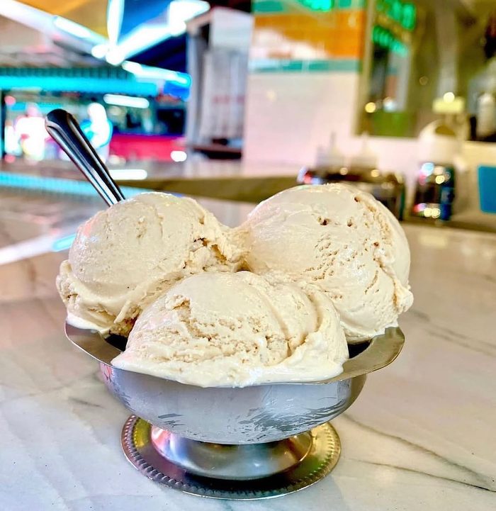 Three pale scoops in a footed silver dish on the marble counter.